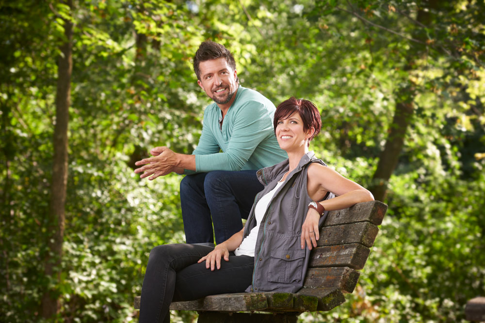 Male model and female model sitting on a park bench outside